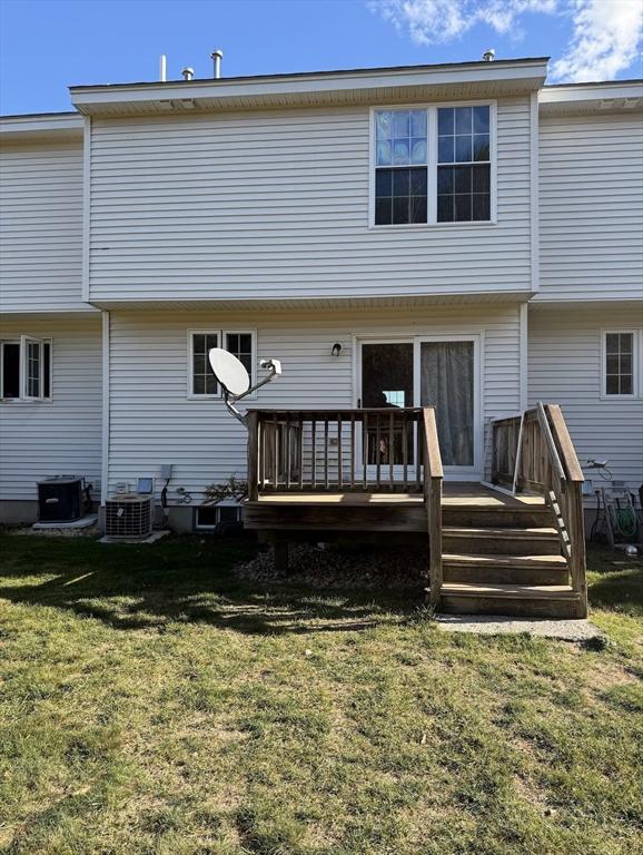 back of house with central AC, a deck, and a lawn