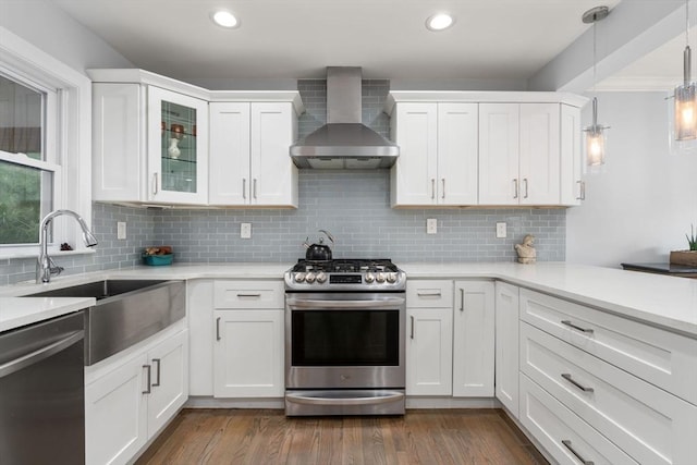 kitchen with light countertops, recessed lighting, appliances with stainless steel finishes, and wall chimney exhaust hood