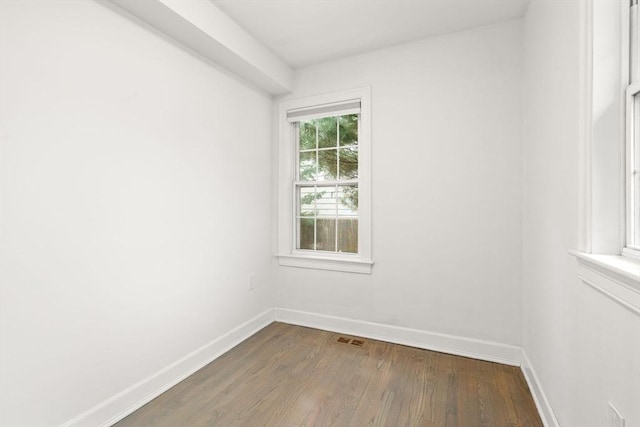 empty room with baseboards, visible vents, and wood finished floors