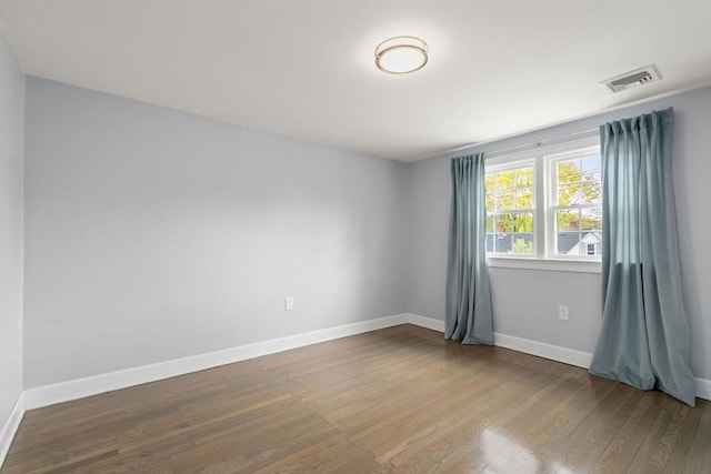 spare room featuring visible vents, baseboards, and wood finished floors