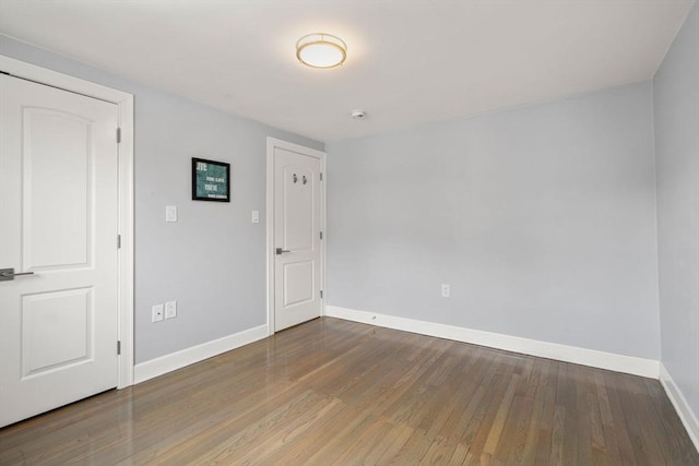 spare room featuring baseboards and wood finished floors