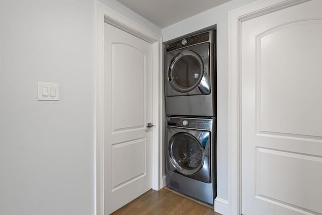 laundry area featuring laundry area, stacked washer and clothes dryer, and dark wood-type flooring