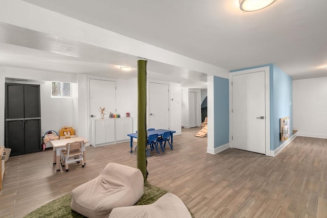 game room with baseboards and light wood finished floors