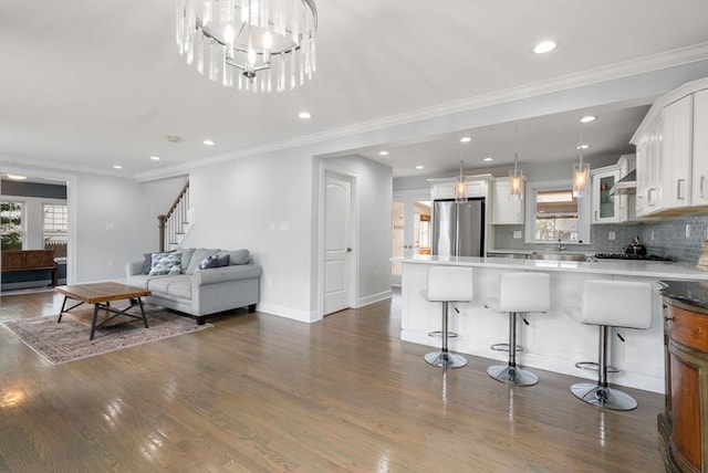 living area featuring plenty of natural light, crown molding, stairs, and dark wood-type flooring