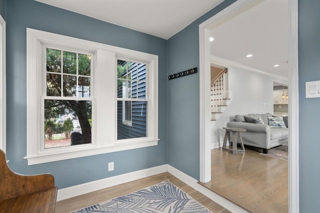 entryway with crown molding, wood finished floors, stairway, baseboards, and recessed lighting