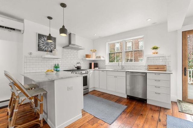 kitchen featuring a wall unit AC, open shelves, appliances with stainless steel finishes, wall chimney range hood, and a peninsula