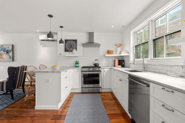 kitchen with open shelves, appliances with stainless steel finishes, a sink, a peninsula, and wall chimney exhaust hood