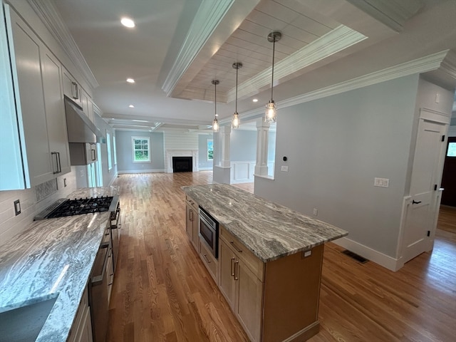 kitchen with light stone countertops, a raised ceiling, a center island, hardwood / wood-style floors, and white cabinets