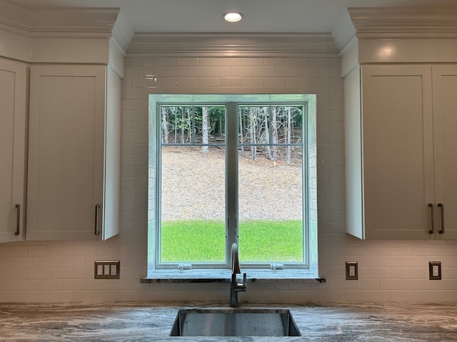 kitchen with crown molding, a healthy amount of sunlight, light stone countertops, and white cabinets