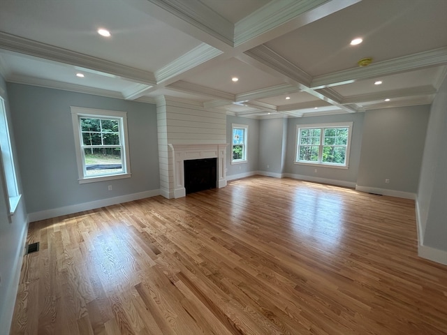 unfurnished living room featuring coffered ceiling, beam ceiling, crown molding, a fireplace, and light hardwood / wood-style floors