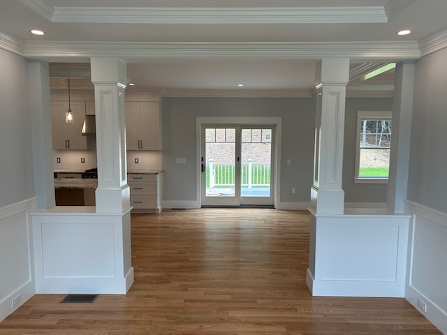 interior space with crown molding, hardwood / wood-style floors, a healthy amount of sunlight, and decorative columns