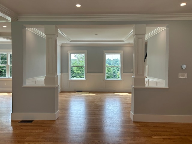 empty room with decorative columns, light hardwood / wood-style flooring, and ornamental molding