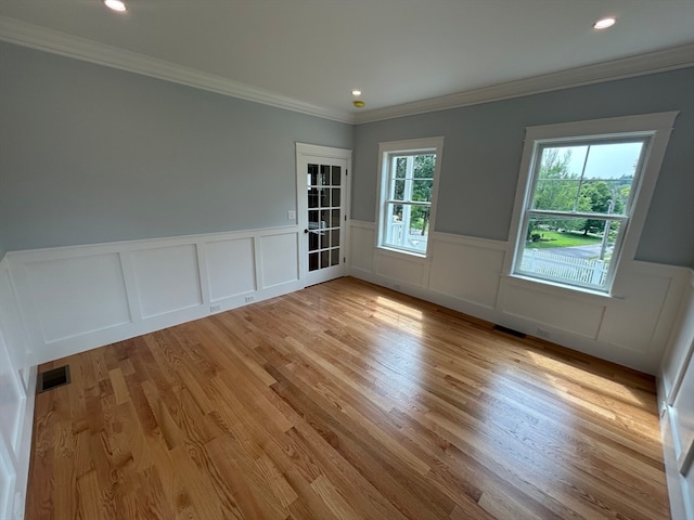 empty room with crown molding and light hardwood / wood-style flooring