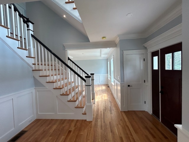 foyer with crown molding, vaulted ceiling, and wood-type flooring