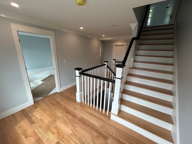 stairway with ornamental molding and hardwood / wood-style floors