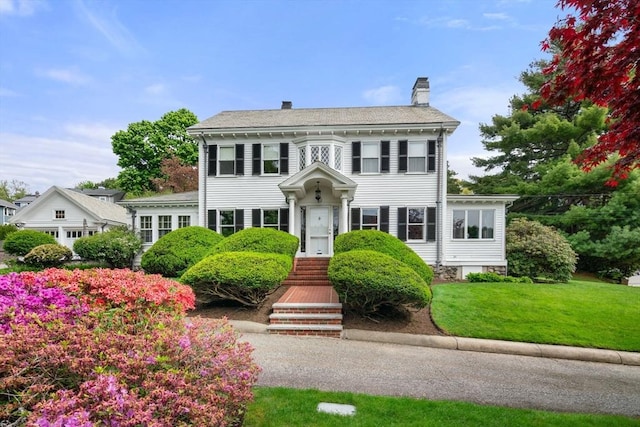 view of front of home with a chimney and a front yard