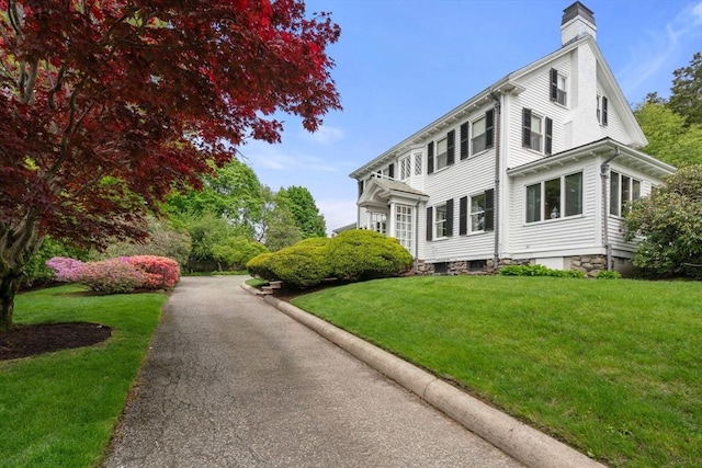 view of property exterior featuring a lawn and a chimney