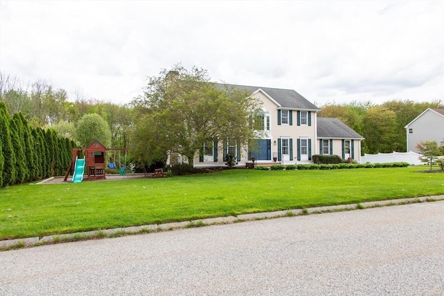 colonial inspired home with a playground and a front lawn