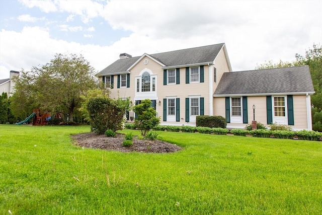 colonial house featuring a chimney, a front lawn, and a shingled roof