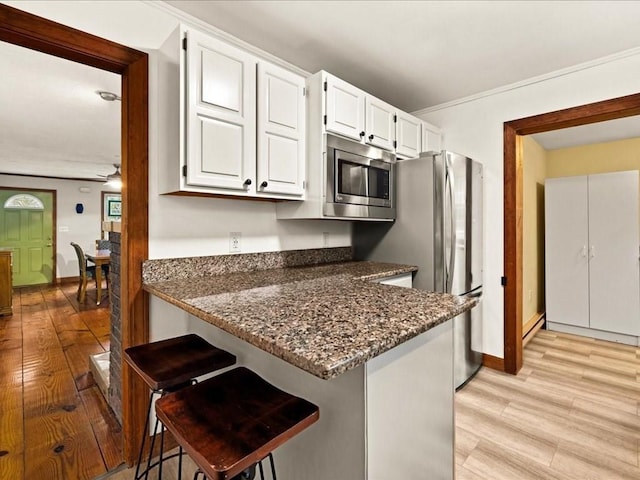 kitchen featuring white cabinets, appliances with stainless steel finishes, dark stone countertops, and ceiling fan