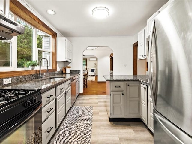 kitchen featuring stainless steel appliances, sink, white cabinets, dark stone countertops, and ventilation hood