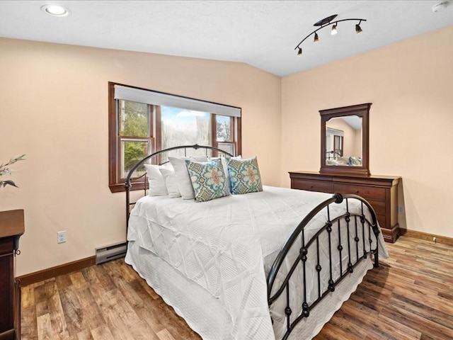 bedroom featuring baseboard heating, hardwood / wood-style floors, and lofted ceiling