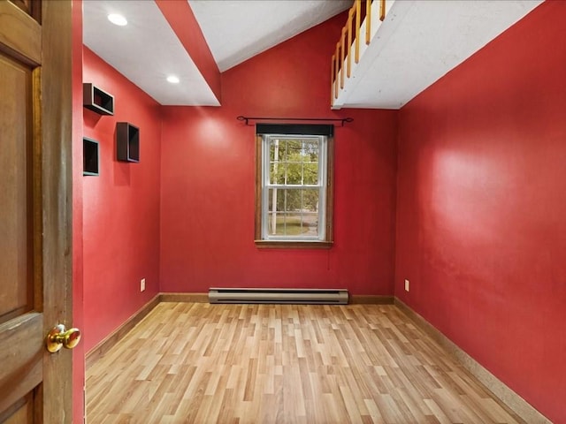 unfurnished room with lofted ceiling, a baseboard heating unit, and light hardwood / wood-style flooring