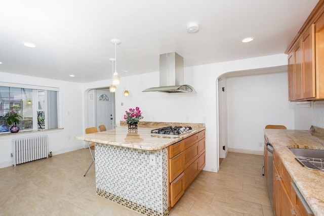 kitchen with light stone countertops, radiator, island exhaust hood, hanging light fixtures, and stainless steel appliances