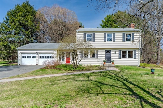 view of front of property with a front lawn, an attached garage, driveway, and a chimney