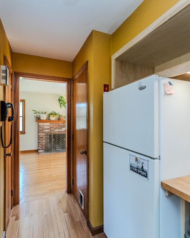 kitchen with baseboards, light wood-style floors, visible vents, and freestanding refrigerator