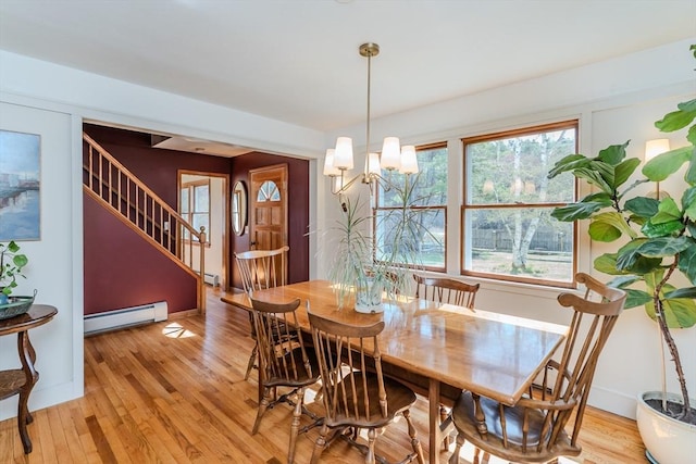 dining space with baseboard heating, baseboards, stairs, and light wood-style flooring