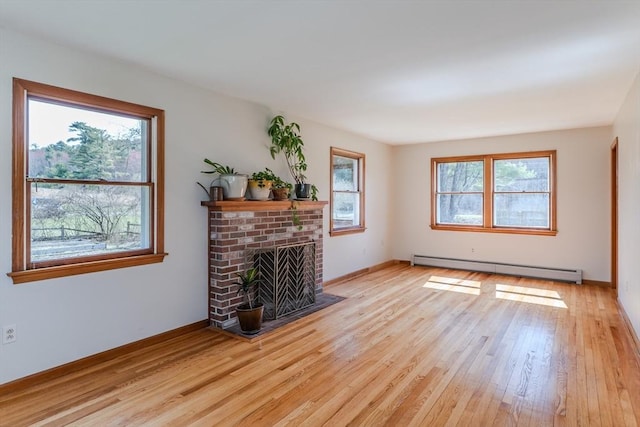 living area with a baseboard radiator, a brick fireplace, light wood finished floors, and baseboards
