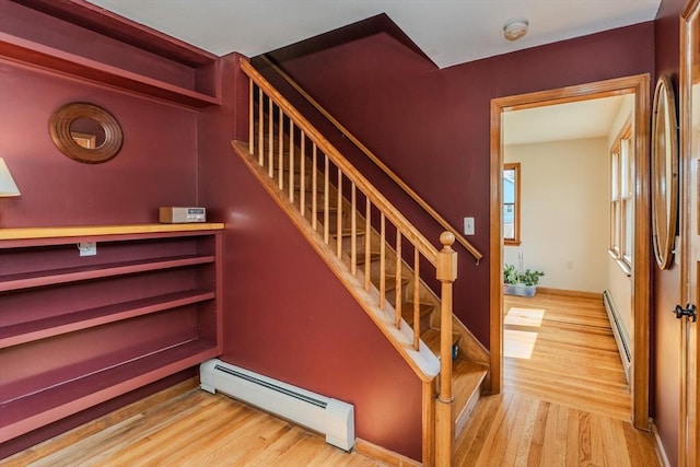 stairs featuring baseboard heating, a baseboard heating unit, and wood finished floors
