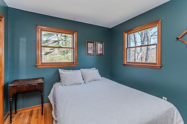 bedroom featuring baseboards, multiple windows, and wood finished floors