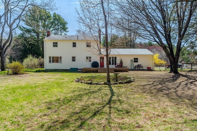 back of house featuring a wooden deck, a yard, a chimney, and fence