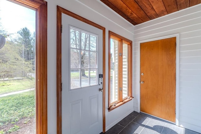 doorway to outside featuring wood ceiling, plenty of natural light, and dark tile patterned floors