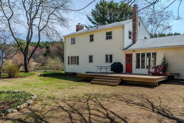 back of property with a yard, a chimney, and a deck