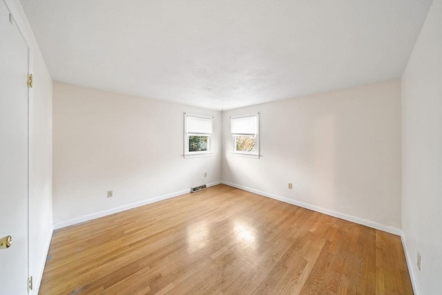 spare room with light wood-style floors, baseboards, and visible vents