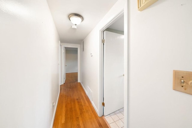 hall with light wood finished floors and baseboards