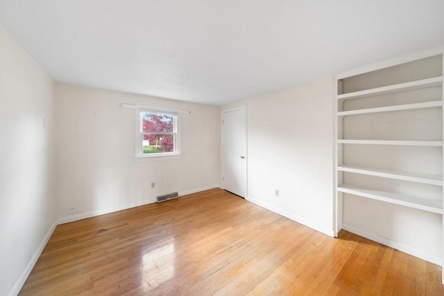 unfurnished bedroom with baseboards, visible vents, and wood finished floors