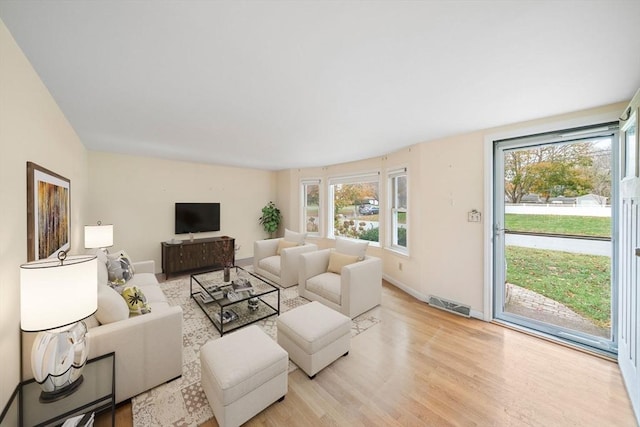 living room with baseboards, visible vents, and light wood-style floors