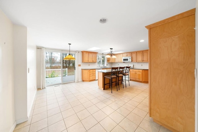 kitchen with a breakfast bar area, light countertops, backsplash, a kitchen island, and white appliances