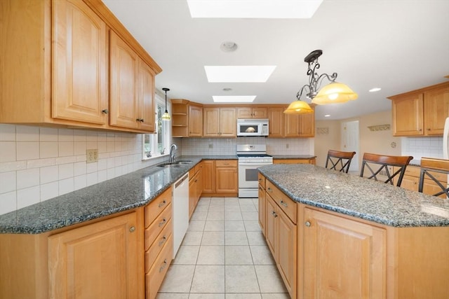 kitchen with a breakfast bar, a skylight, hanging light fixtures, a kitchen island, and white appliances