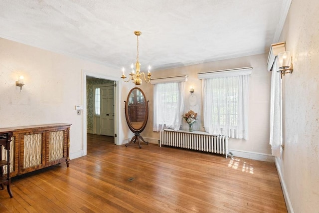 foyer entrance featuring radiator heating unit, a chandelier, wood-type flooring, ornamental molding, and baseboards