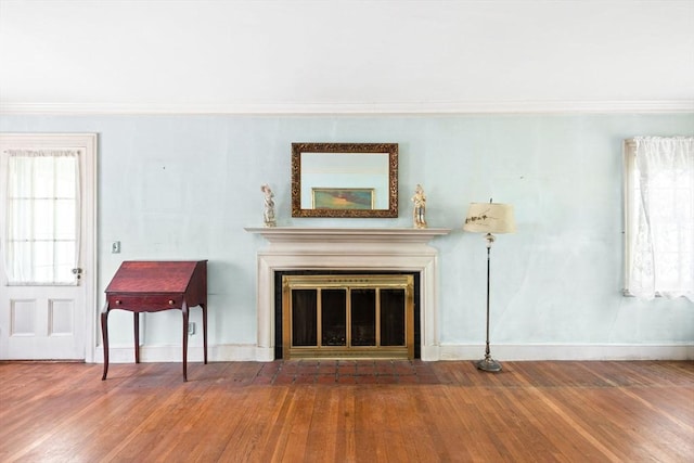 living room with wood finished floors, baseboards, crown molding, and a fireplace with flush hearth