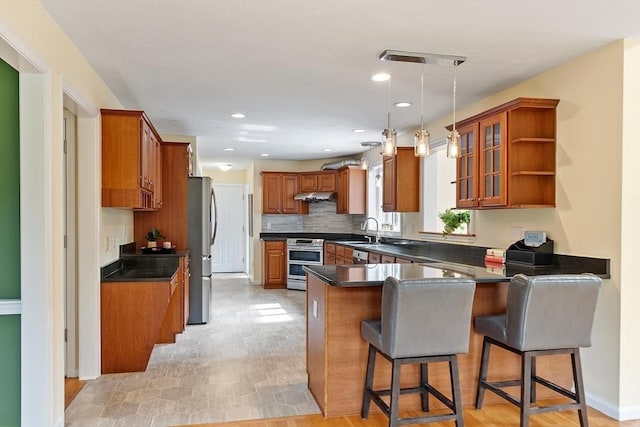 31 Fort Pond Hill Rd, Littleton, MA 01460 - kitchen featuring stainless steel appliances, a peninsula, brown cabinetry, under cabinet range hood, and dark countertops