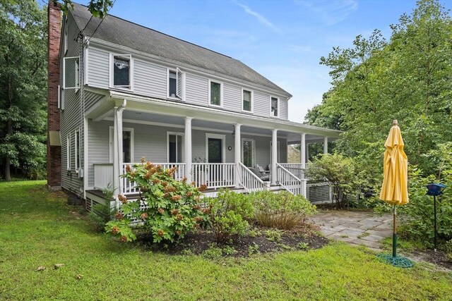 back of property with covered porch and a yard