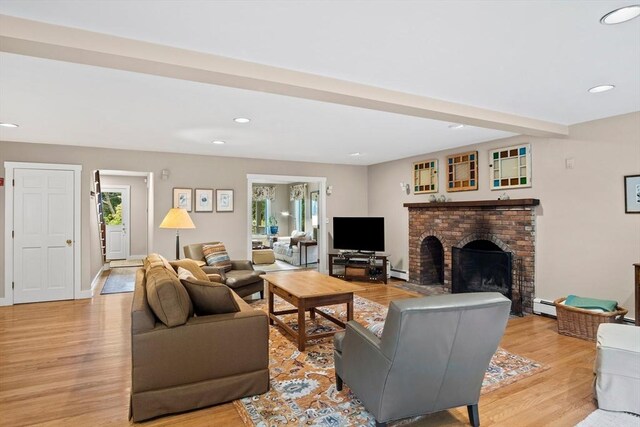 living room with a fireplace, beamed ceiling, baseboard heating, and light hardwood / wood-style floors