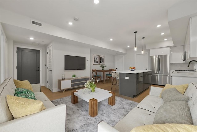 living room with light wood-type flooring, recessed lighting, and visible vents