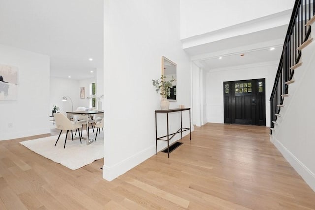 foyer featuring crown molding, stairway, baseboards, light wood finished floors, and recessed lighting